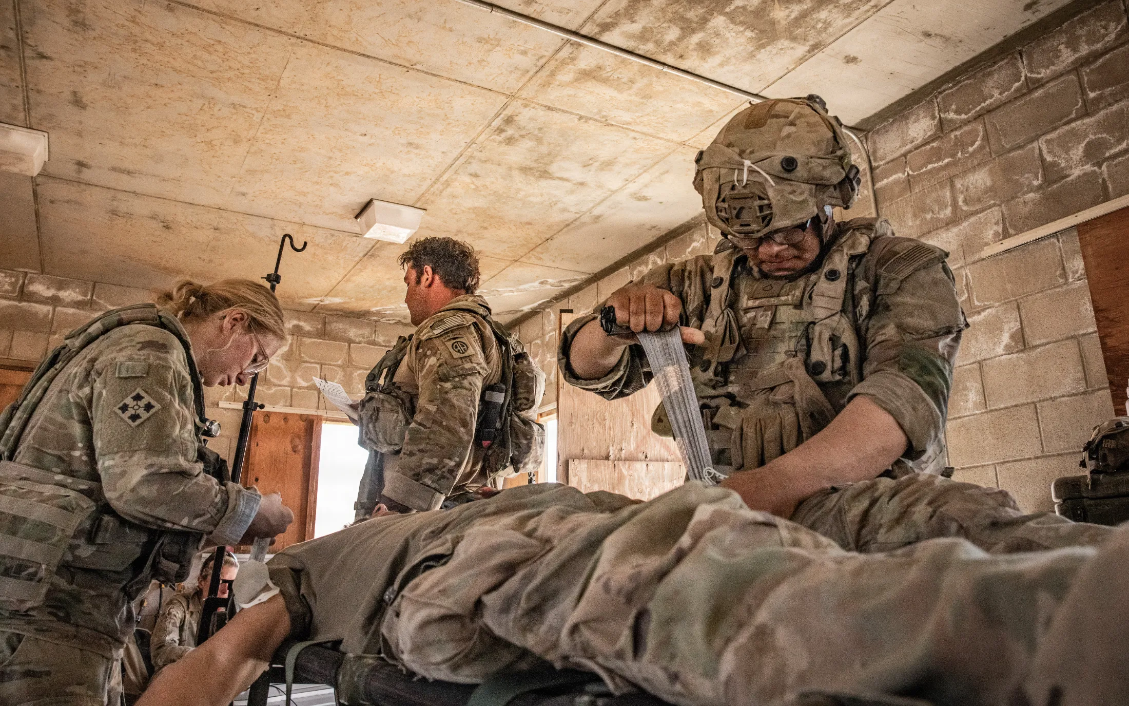 Combat medics treating a casualty on a litter at a forward aid station