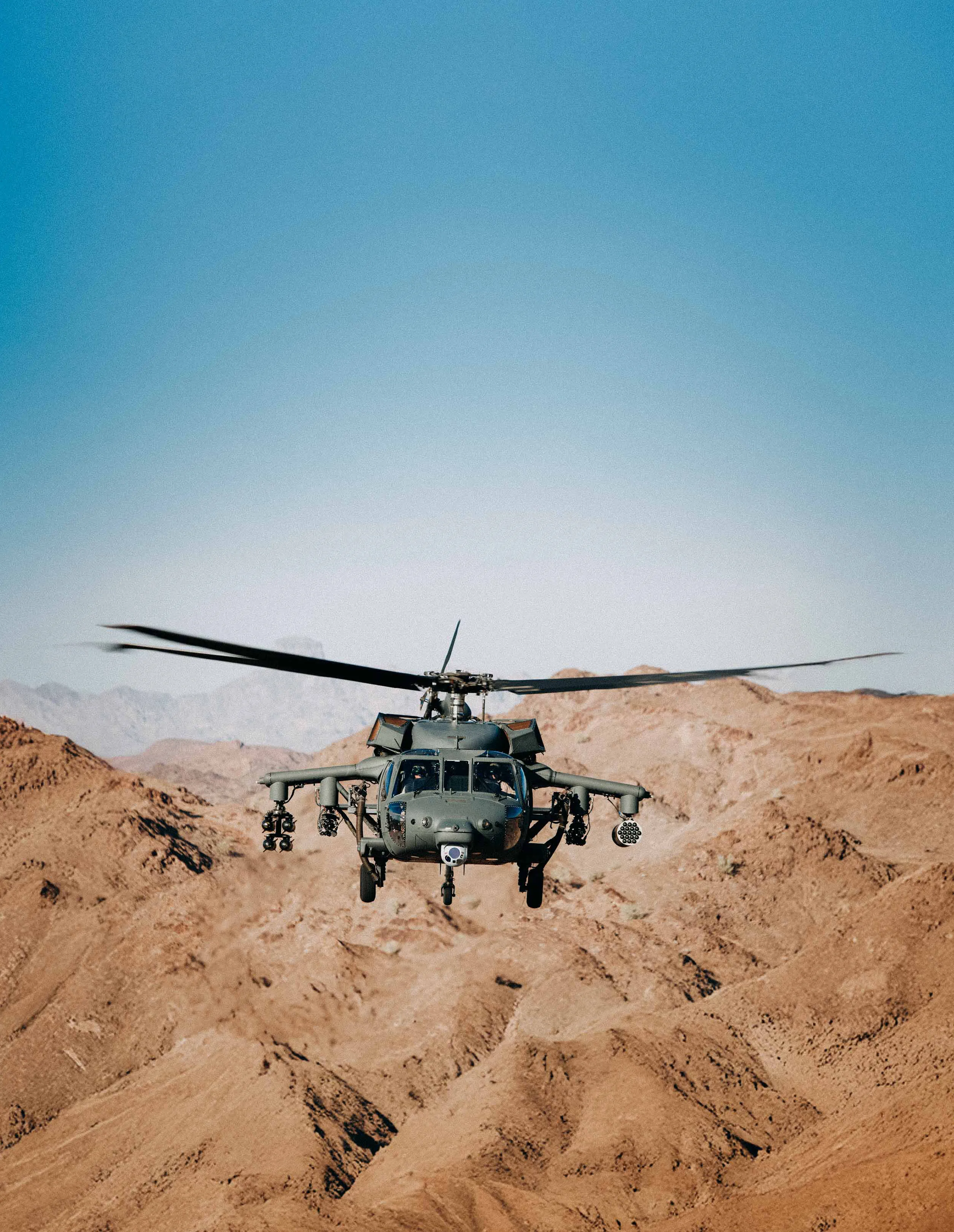 A UH-60 Black Hawk holding a low hover over desert terrain