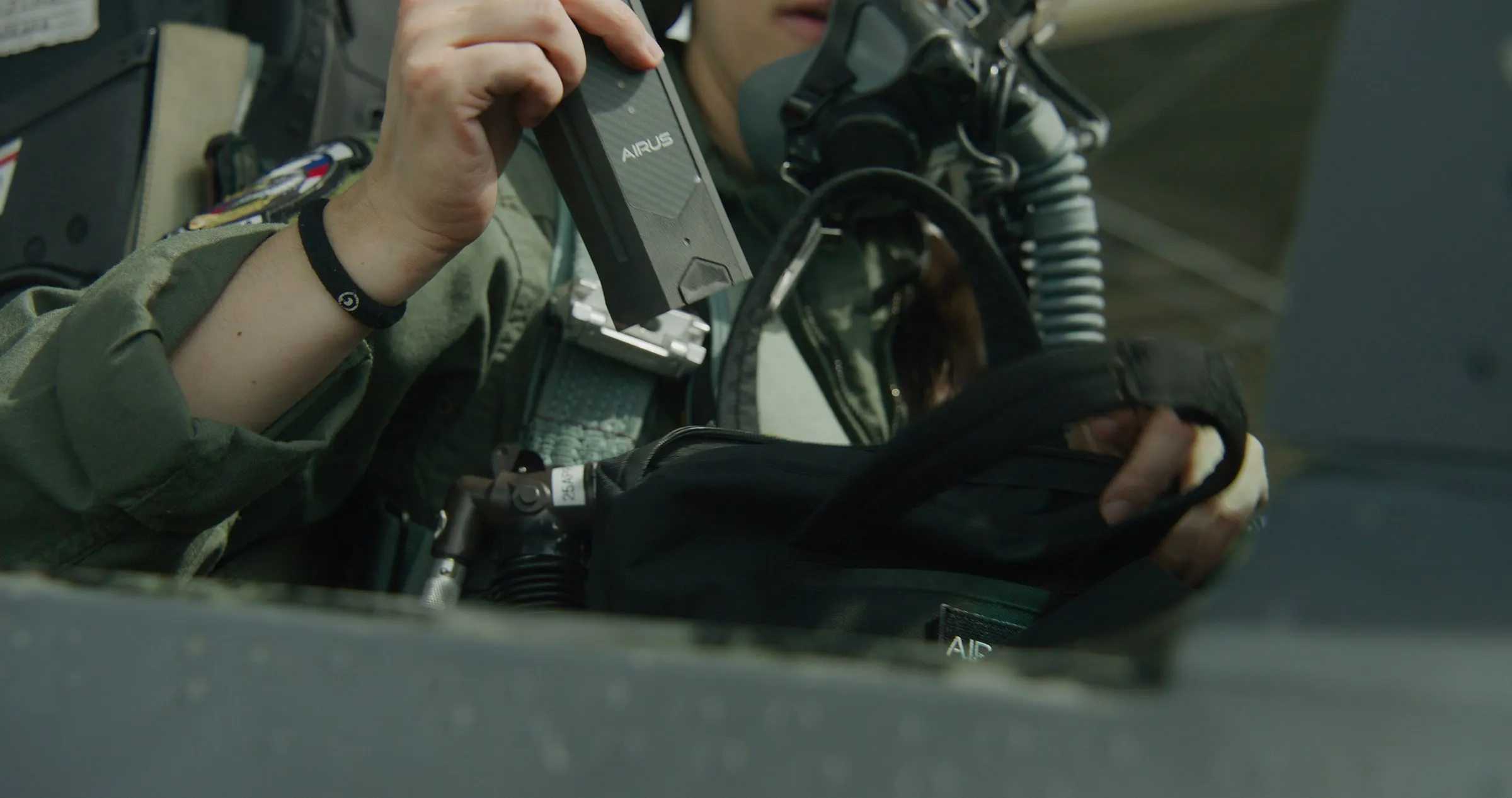 Aircrew stowing the AIRUS controller without unstrapping, seated in the cockpit