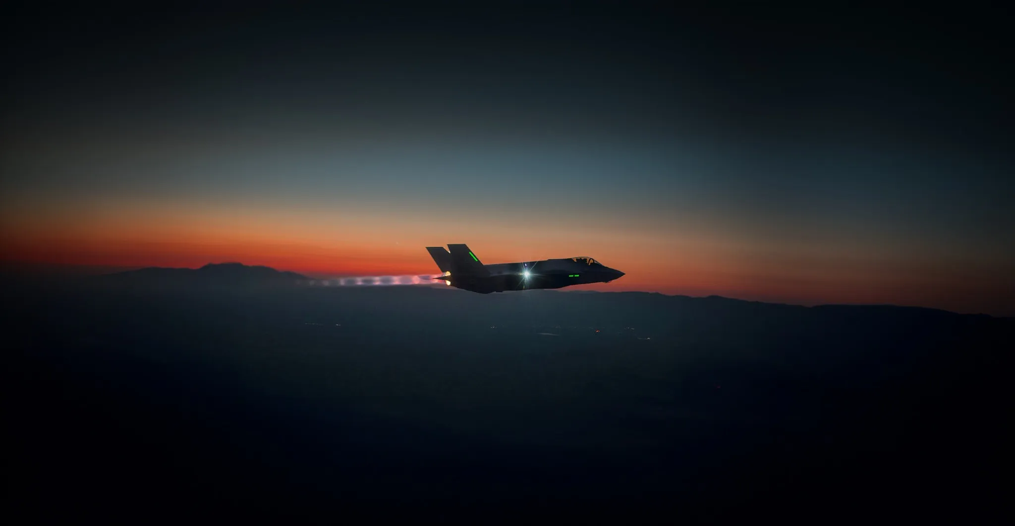 An F-35 in level flight against a dusk horizon